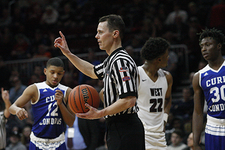 Basketball official holds ball to make a call.